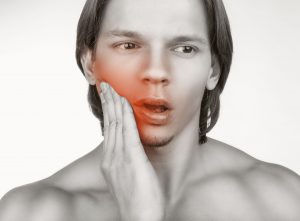 Young male holding cheek in pain   sf oral surgery Young male holding cheek in pain   sf oral surgery