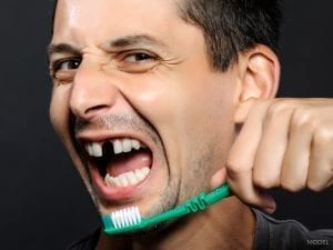 Man with Missing Front Tooth Holding Up Toothbrush
