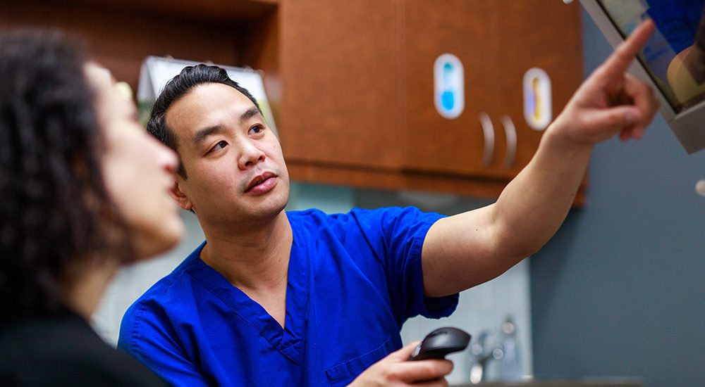 Dr Chan pointing at screen talking to patient sf oral surgery