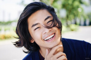 Smiling Young Man with long Hair Blowing in His Face