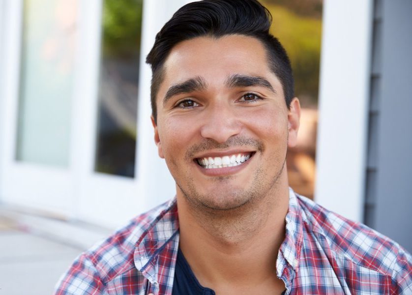 Young man in a flannel shirt with a wide and bright smile   sf oral surgery