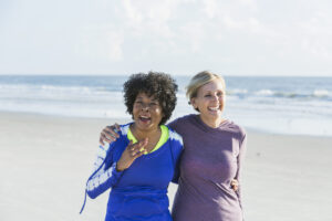 Two Older Ladies Smiling and Embracing at the Beach